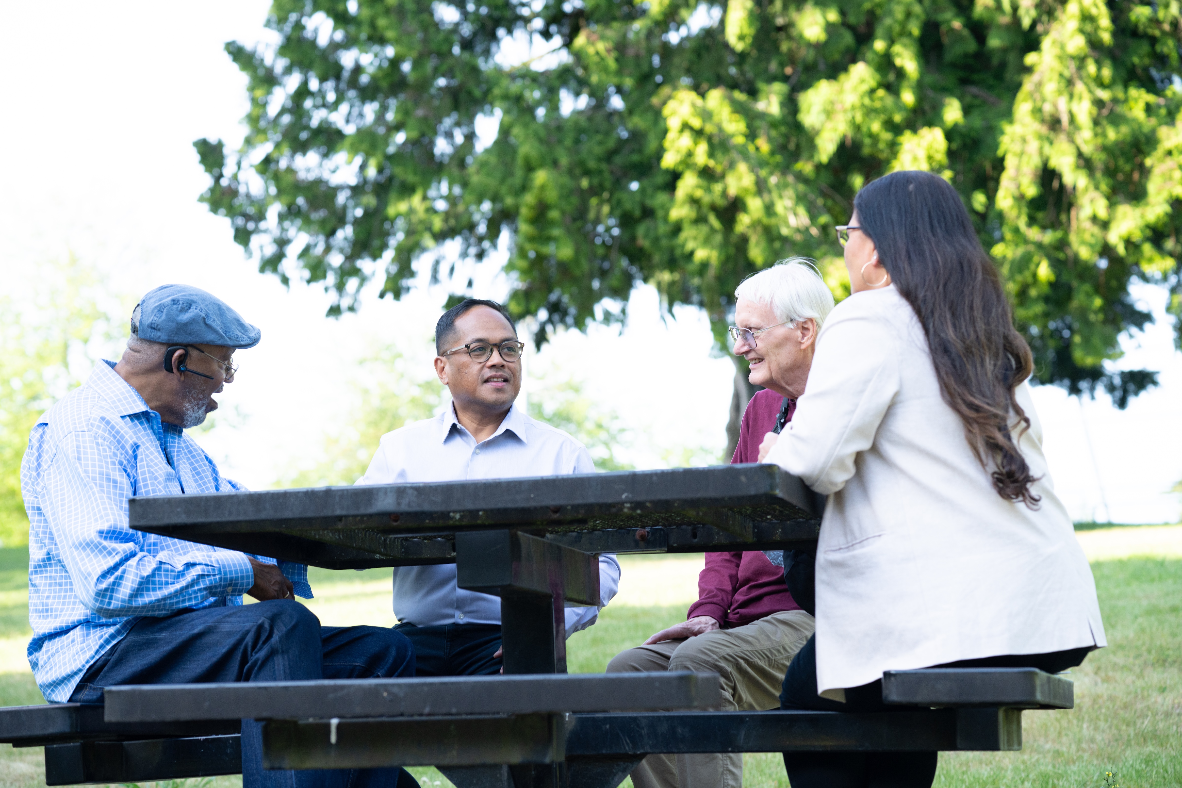 Edwin talking with community members at a park picnic table