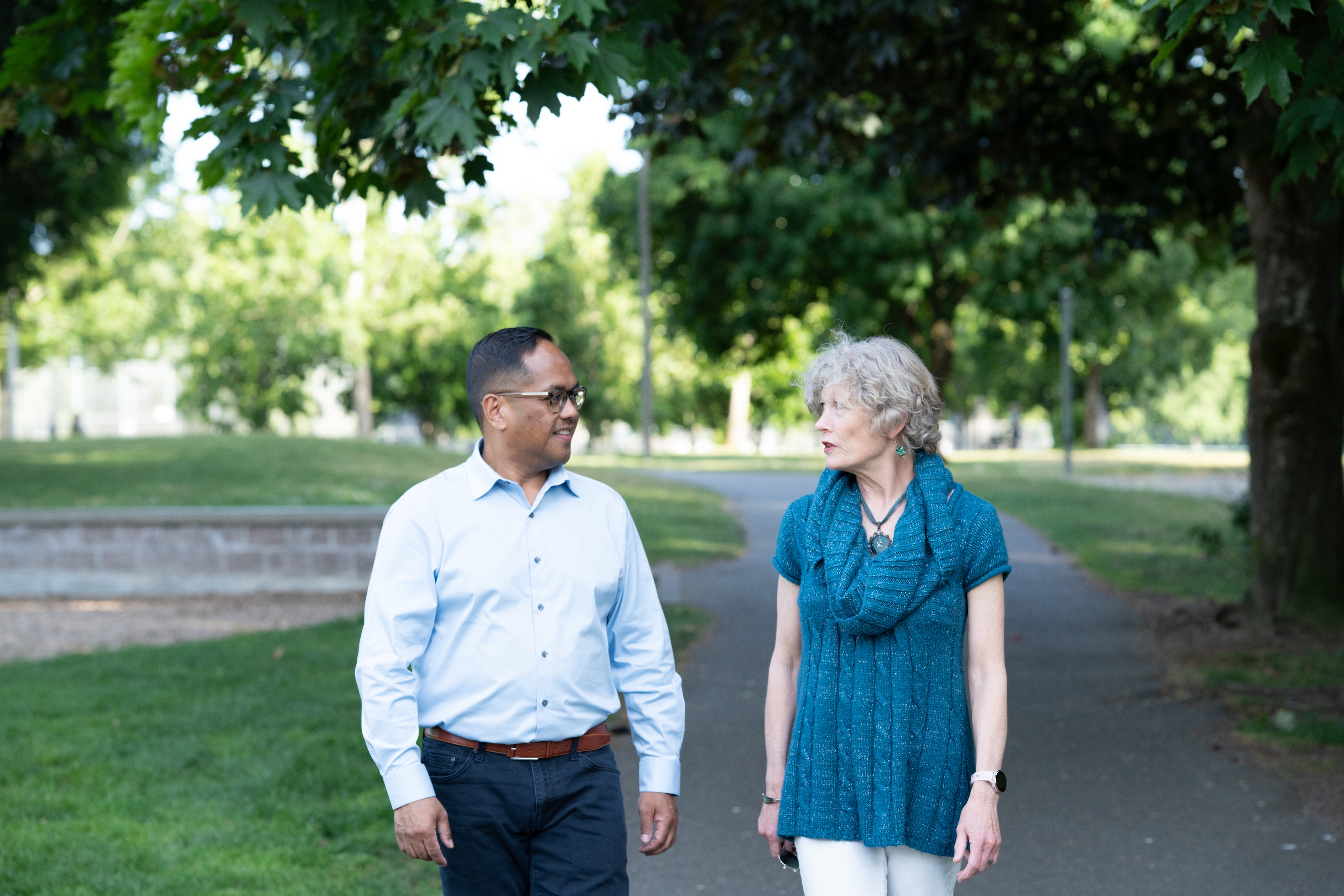 Edwin walking and talking with a neighbor on a tree-lined path